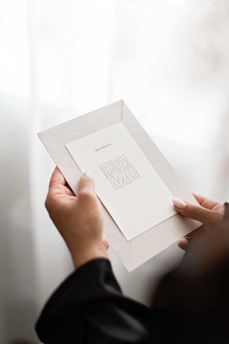 Flat lay of a complete wedding stationery suite with envelope, invitation, RSVP card, wax seal, and dried botanicals arranged on a marble surface